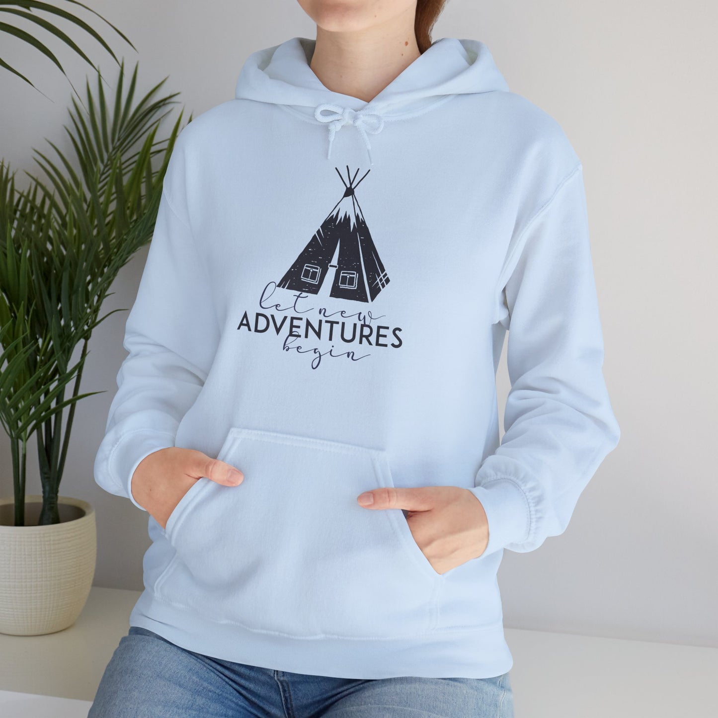 A person wearing a light blue hooded sweatshirt with 'Adventures' text and a tribal design on the front.