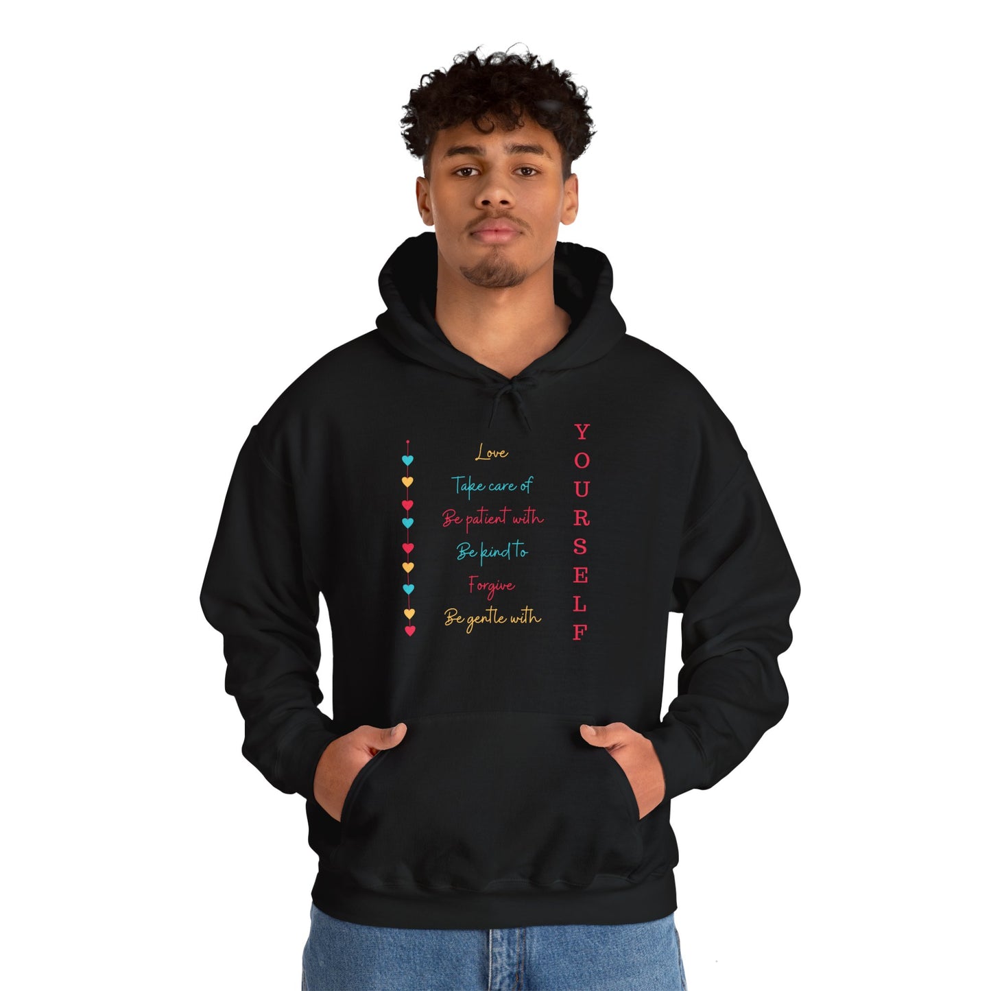 A person wearing a black unisex hooded sweatshirt with a 'Love Yourself' design in colorful hearts.