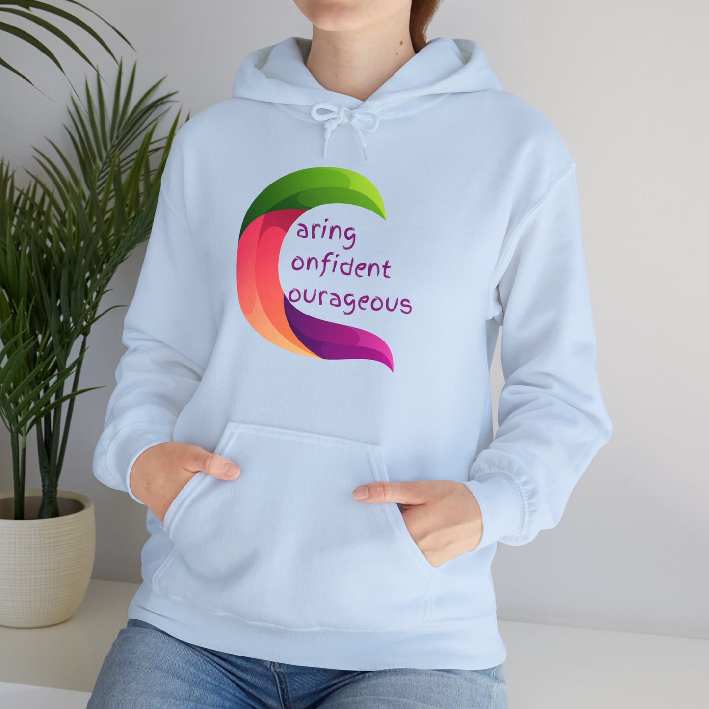 A person wearing a blue unisex hooded sweatshirt with 'Caring Confident Courageous' printed on the front.