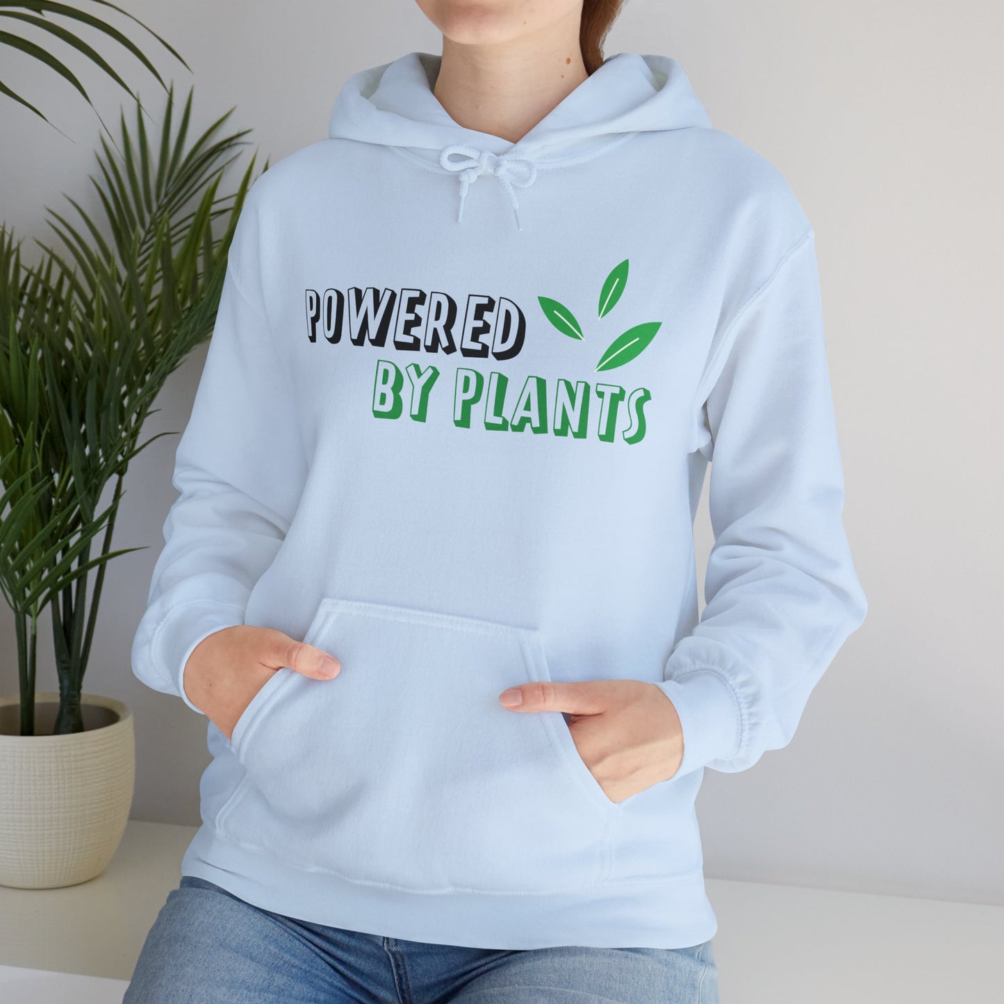 A person wearing a blue hooded sweatshirt with the text 'Powered By Plants' printed on the front.