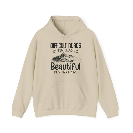 A beige unisex hooded sweatshirt with the text 'DIFFICULT ROADs OFTEN LEAD TO BEAUTIFUL DESTINATIONS' printed on the front.