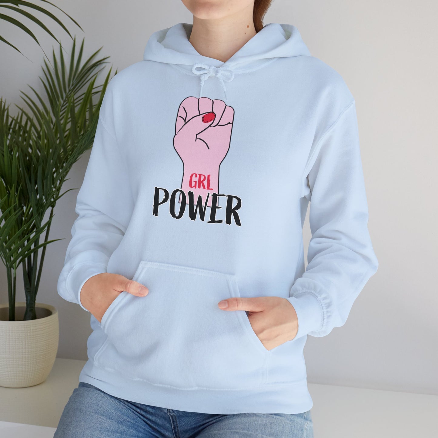 A person wearing a light blue unisex hooded sweatshirt with 'GRL Power' text and a pink fist design on the front.