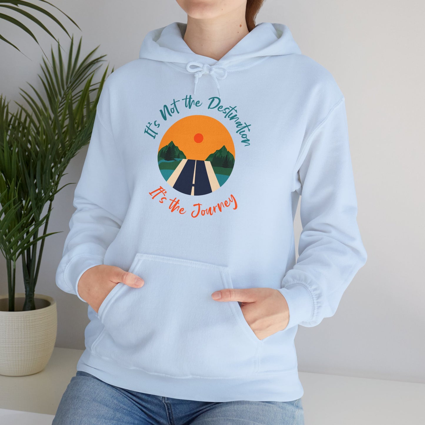 A person wearing a blue hooded sweatshirt with 'It's Not The Destination It's The Journey' text and a graphic design featuring a sun and road on the front.