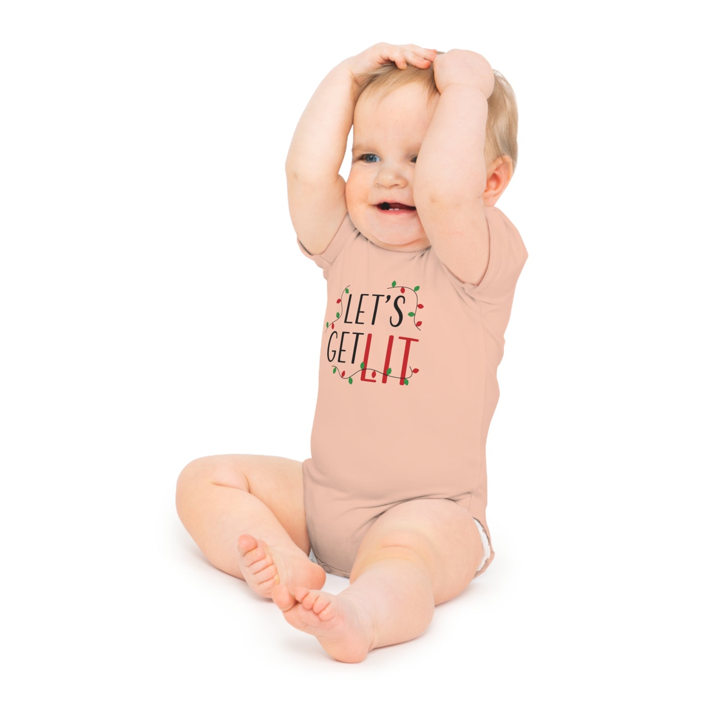 A baby wearing a blush pink bodysuit with the text 'Let's Get Lit' and a Christmas-themed design.