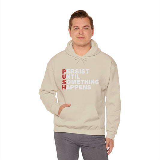 A person wearing a biege unisex hooded sweatshirt with the text 'PUSH Persist Until Something Happens' printed in white on the front.