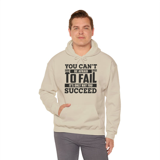 A male model wearing a beige unisex hooded sweatshirt with the text 'You Can't Be Afraid To FAIL' printed on the front.