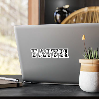 A 'Faith' sticker with a kiss-cut border, displayed on a laptop, with a potted plant and other items in the background.