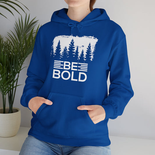 A person wearing a blue unisex hooded sweatshirt with 'BE BOLD' text design and a forest and tree graphic on the front.