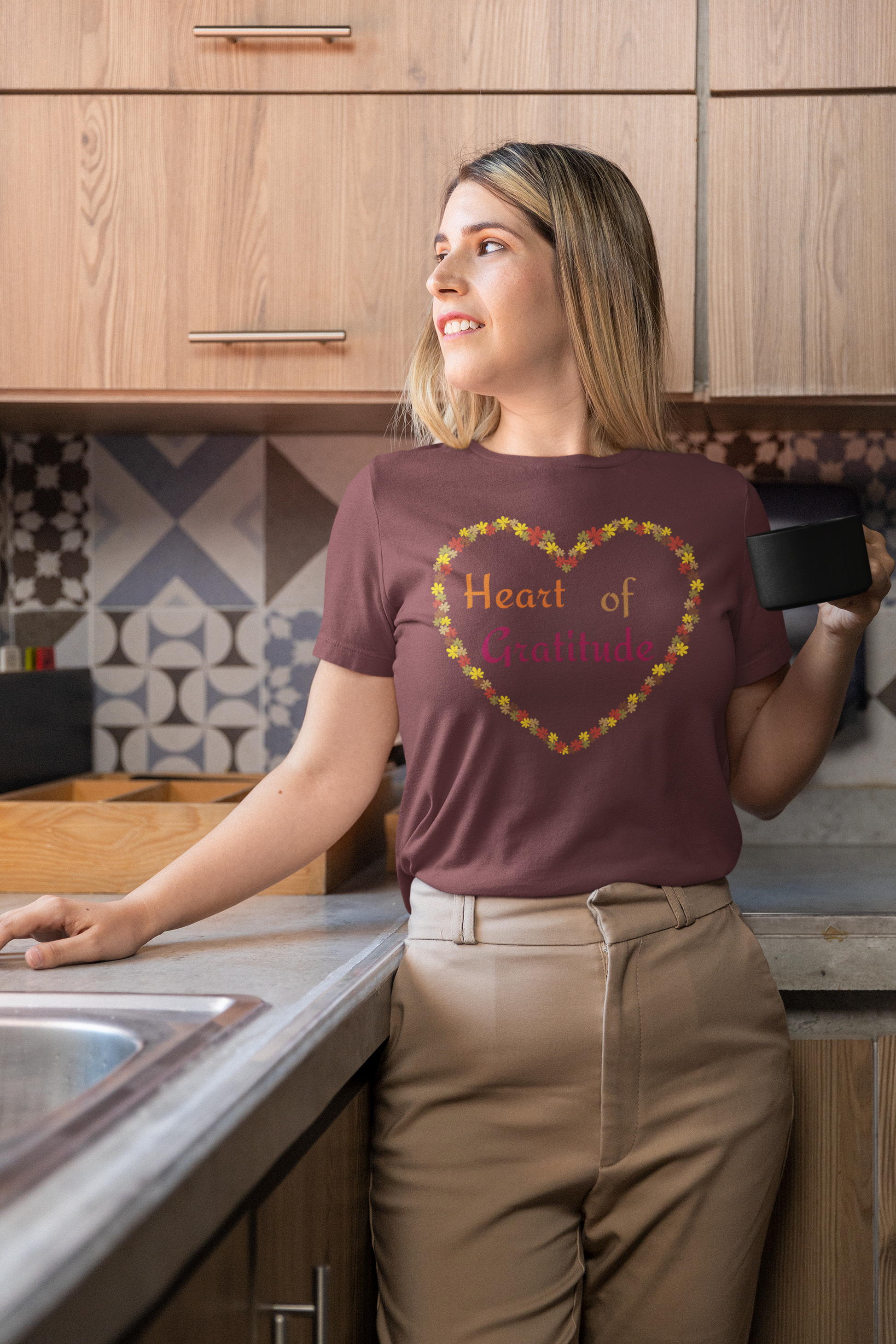 Woman holding coffee mug and wearing a maroon color motivational t-shirt design displaying heart of gratitude.