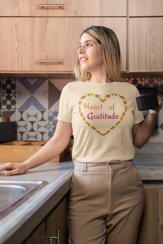 Woman holding coffee mug and wearing a soft cream color motivational t-shirt design displaying heart of gratitude.