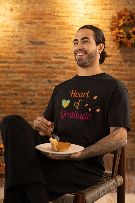 Man with arm tattoo eating pumpkin pie and wearing a black color motivational t-shirt design displaying heart of gratitude.